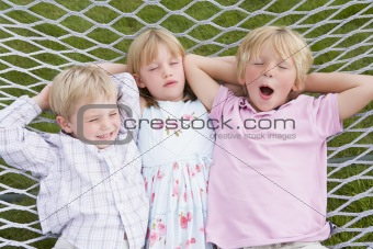 Three children relaxing and sleeping in hammock
