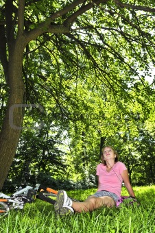 Teenage girl relaxing in a park with her bicycle