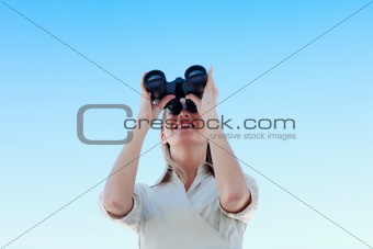 Businesswoman looking through binoculars against blue sky