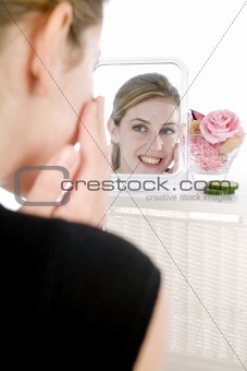 Woman applying facepack in mirror
