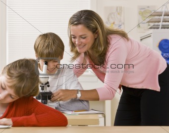 Teacher helping student with microscope