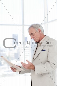 Portrait of a senior manager reading newspaper