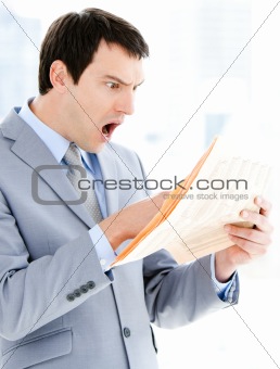 Portrait of a surprised businessman reading a newspaper