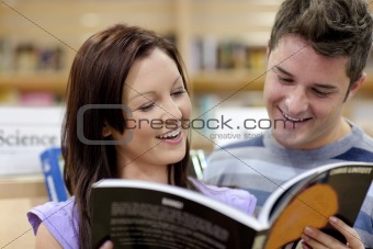 Cheerful couple reading a book in the science department of a bo
