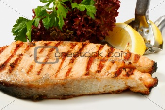 Grilled salmon steak with salad and lemon
