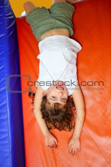 upside down little girl on playground slide laughing