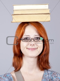 Red-haired girl keep books on her head. Studio shot.