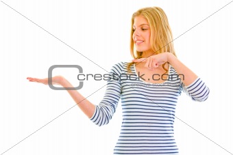 Smiling beautiful teen girl pointing finger on empty hand
