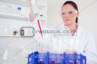 Attractive female biologist holding a manual pipette with sample
