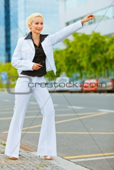  Smiling business woman catching taxi near office center
