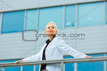  Smiling business woman leaning on railing at office building looking at copyspace 
