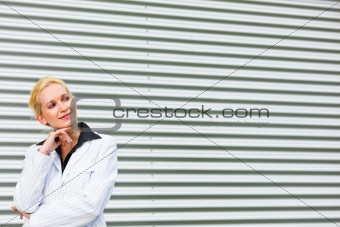  Smiling business woman standing at office building and looking at copyspace 
