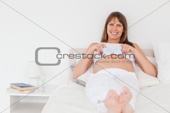 Charming pregnant female playing with little socks while lying o