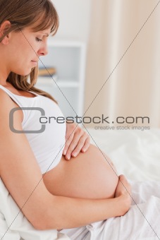 Portrait of a charming pregnant female lying on a bed