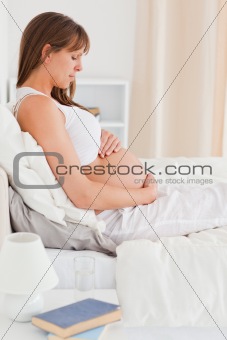 Portrait of a beautiful pregnant female lying on a bed