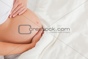 Close-up of a young pregnant female lying on a bed