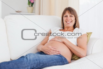 Good looking pregnant woman posing while lying on a sofa