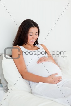 Frontal view of a good looking pregnant woman touching her belly