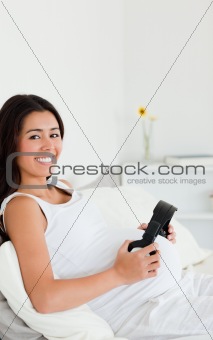Attractive pregnant woman putting headphones on her belly while 