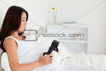 Good looking pregnant woman putting headphones on her belly