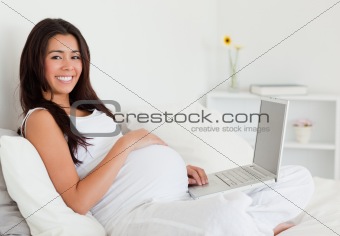 Charming pregnant woman relaxing with her laptop 