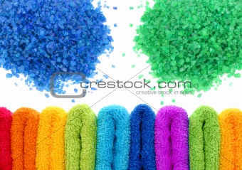 sea bath salt and stacked colorful towels over white background
