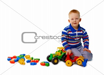 Boy sits on white background with toys