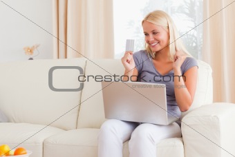Beautiful blonde woman cheering while shopping online