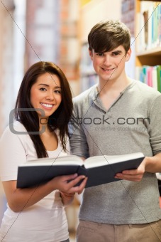 Portrait of good looking students with a book