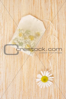Bag of chamomile tea over wooden background - concept