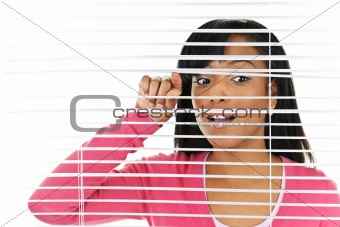 Woman looking through venetian blinds