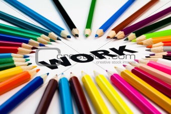 many colored pencils arranged in circle on the word work