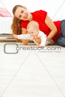 Young mother and cheerful baby playing on floor
