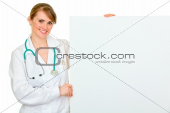 Smiling medical female doctor holding blank billboard
