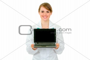 Smiling medical doctor woman showing laptops blank screen
