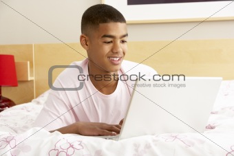 Teenage Boy Using Laptop In Bedroom