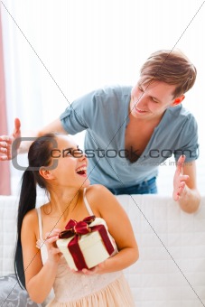 Happy young woman looking on boyfriend who made her surprise

