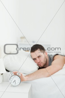Portrait of a man being awakened by an alarm clock