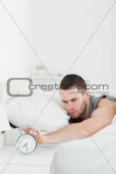 Portrait of a young man being awakened by an alarm clock