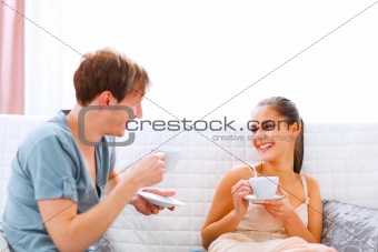 Young couple sitting at couch and drinking coffee
