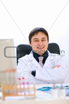 Portrait of smiling medical doctor sitting in cabinet
