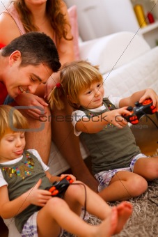 Twins daughters playing on console at home
