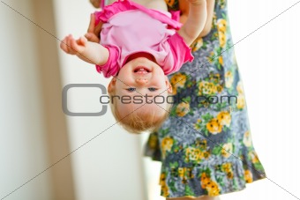 Mother holding smiling baby upside down