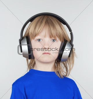 boy with long blond hair listening to music in headphones - isolated on light gray