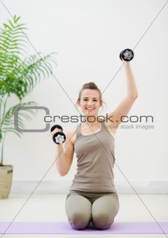 Young woman lifting dumb-bells