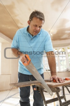 Builder Sawing Wood On Workbench