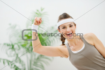Portrait of smiling athletic woman showing biceps