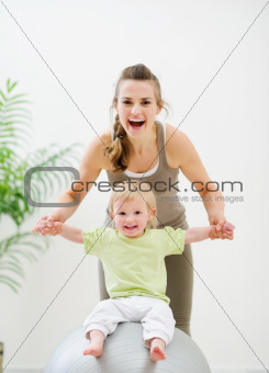 Mother mother holding baby sitting on fitness ball