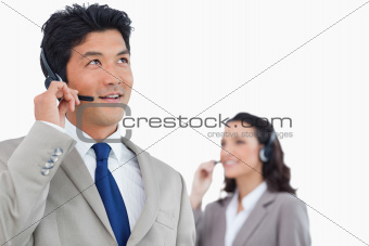 Call center agent with headset and colleague behind him