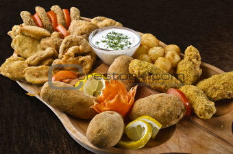 Rustic tray with various meats, cheese balls and garlic sauce- isolated